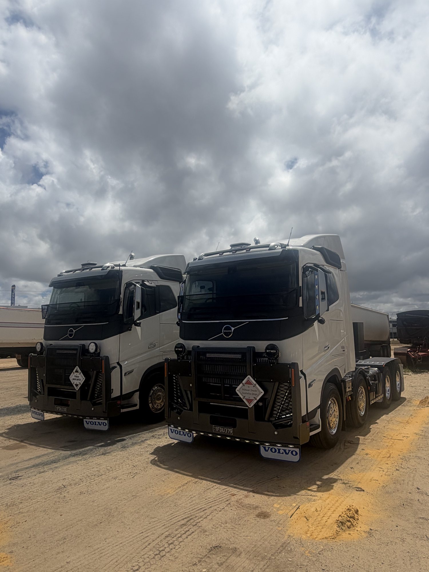 Two white BJ Group Volvo FH prime movers parked in the yard