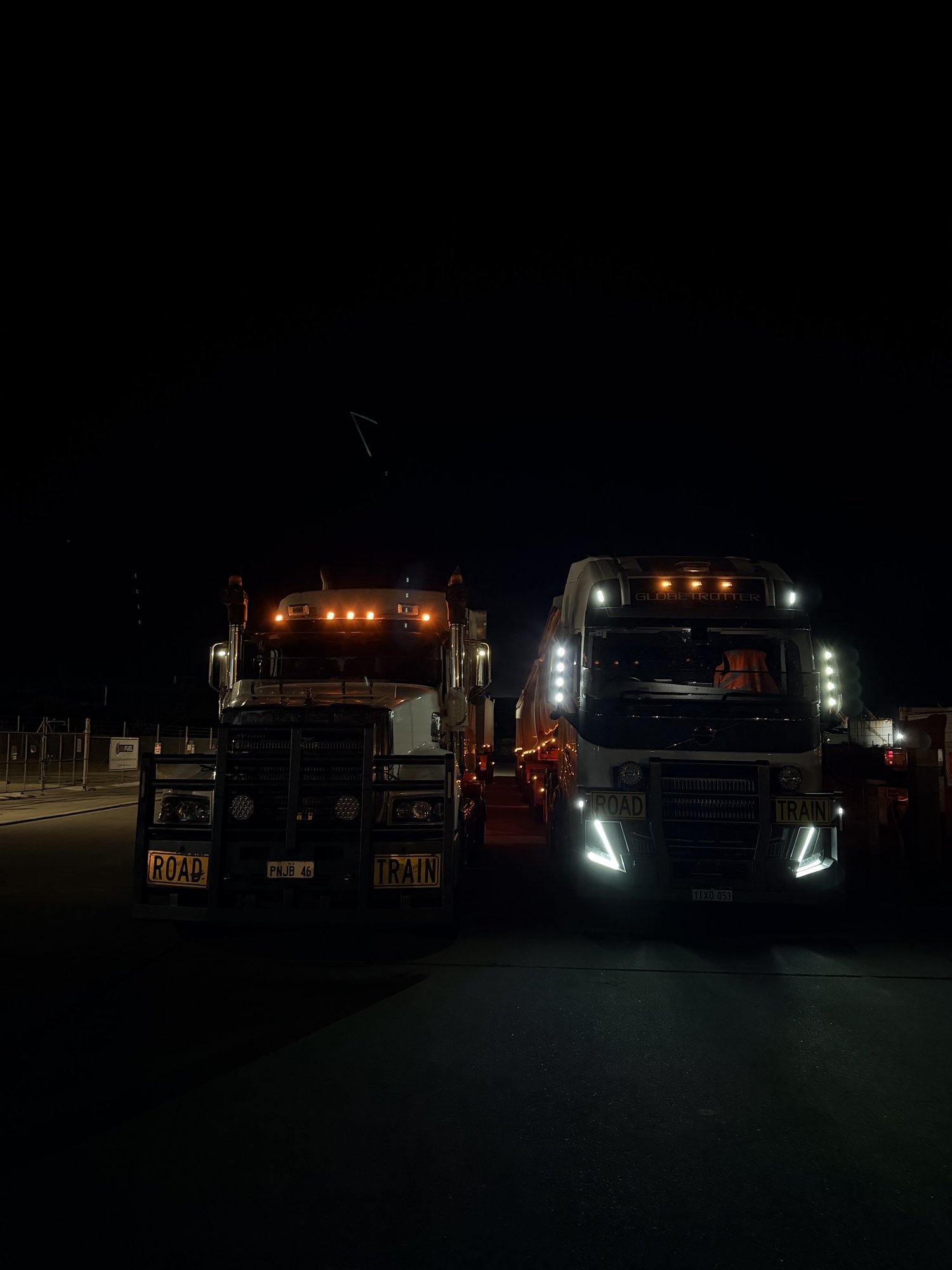 BJ Group Mack and Volvo prime movers side by side at night