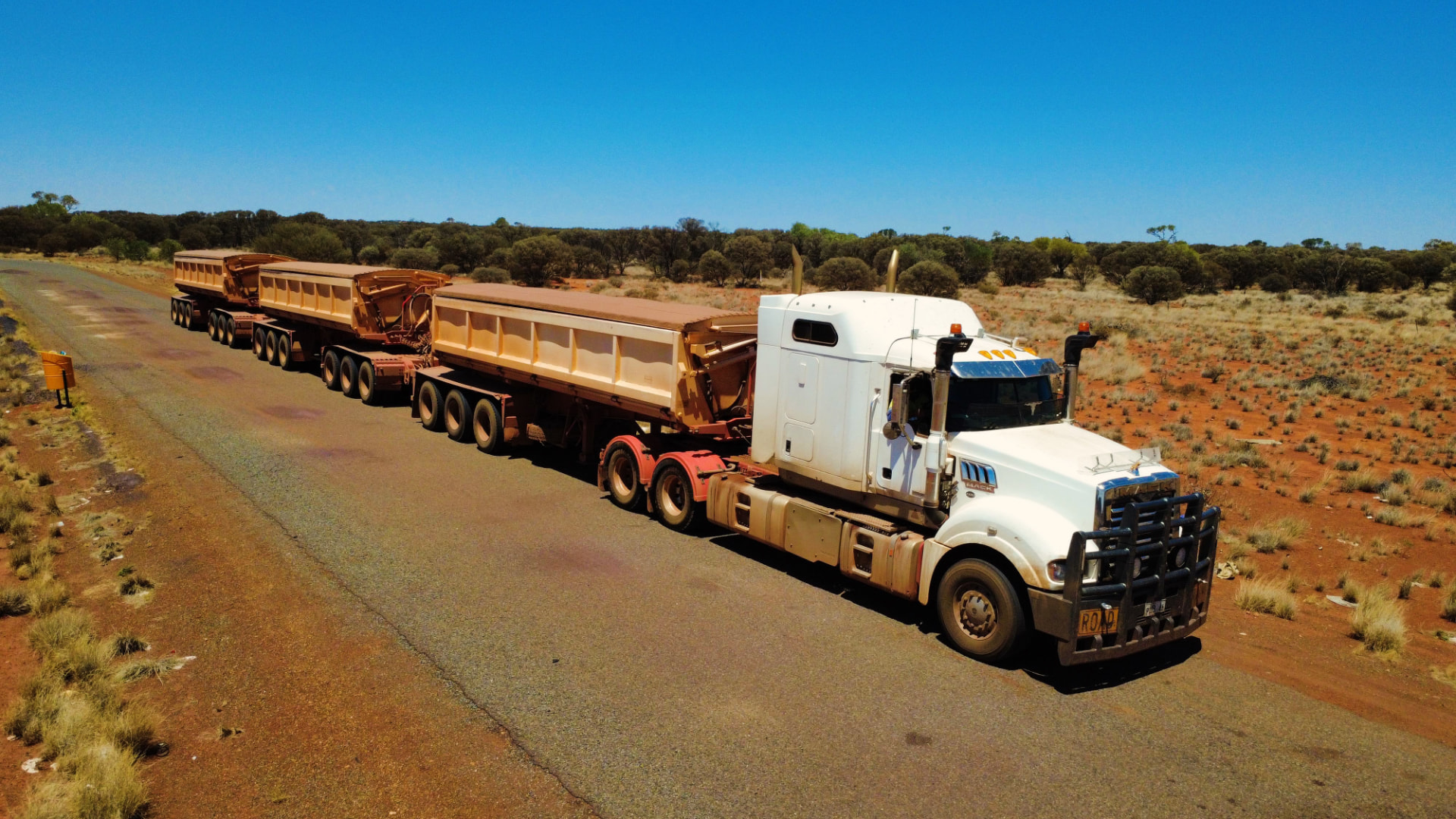 White BJ Group Mack road train with side tippers on a red-dirt outback road